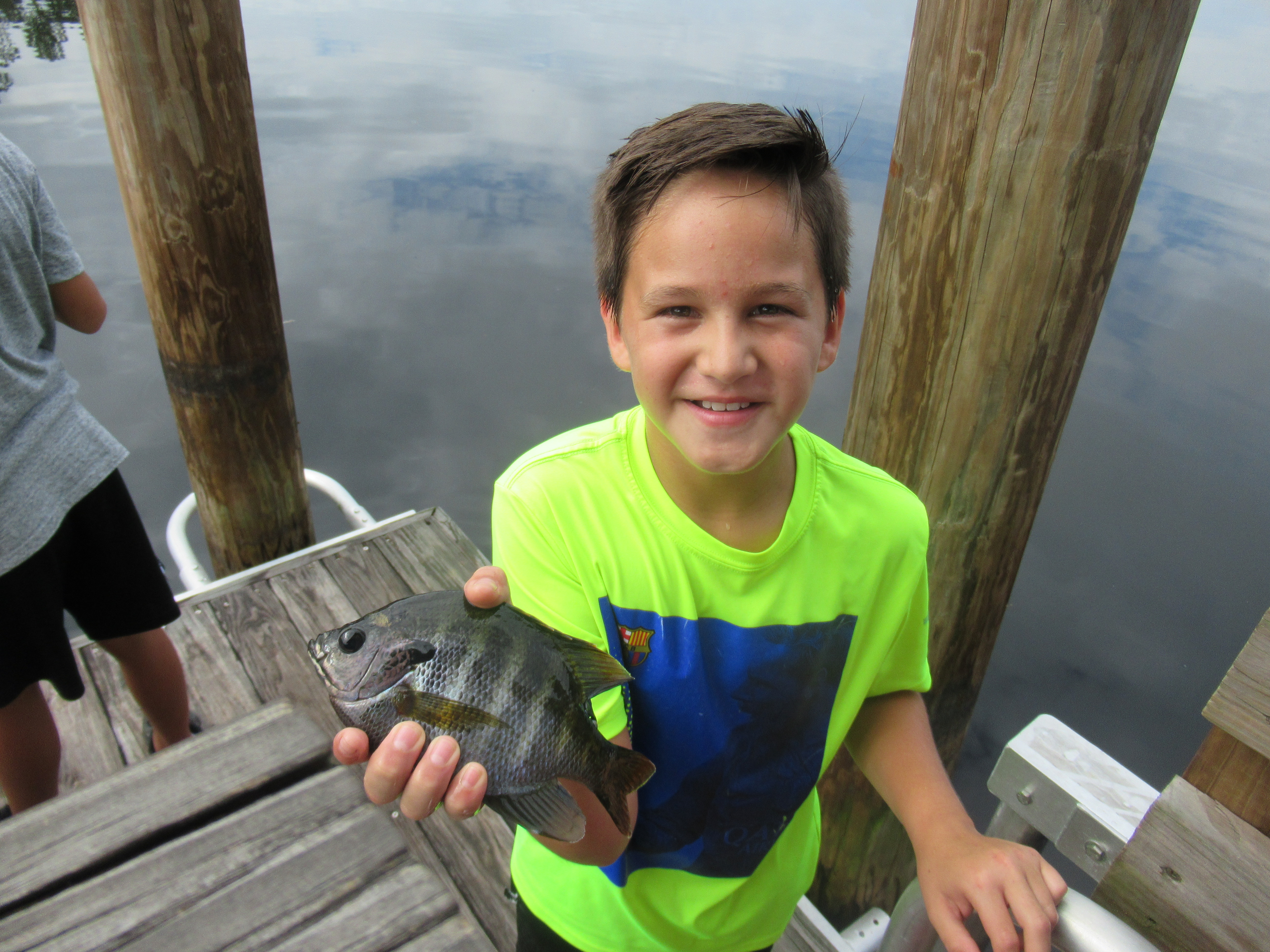 Child on a dock holding a small fish he caught