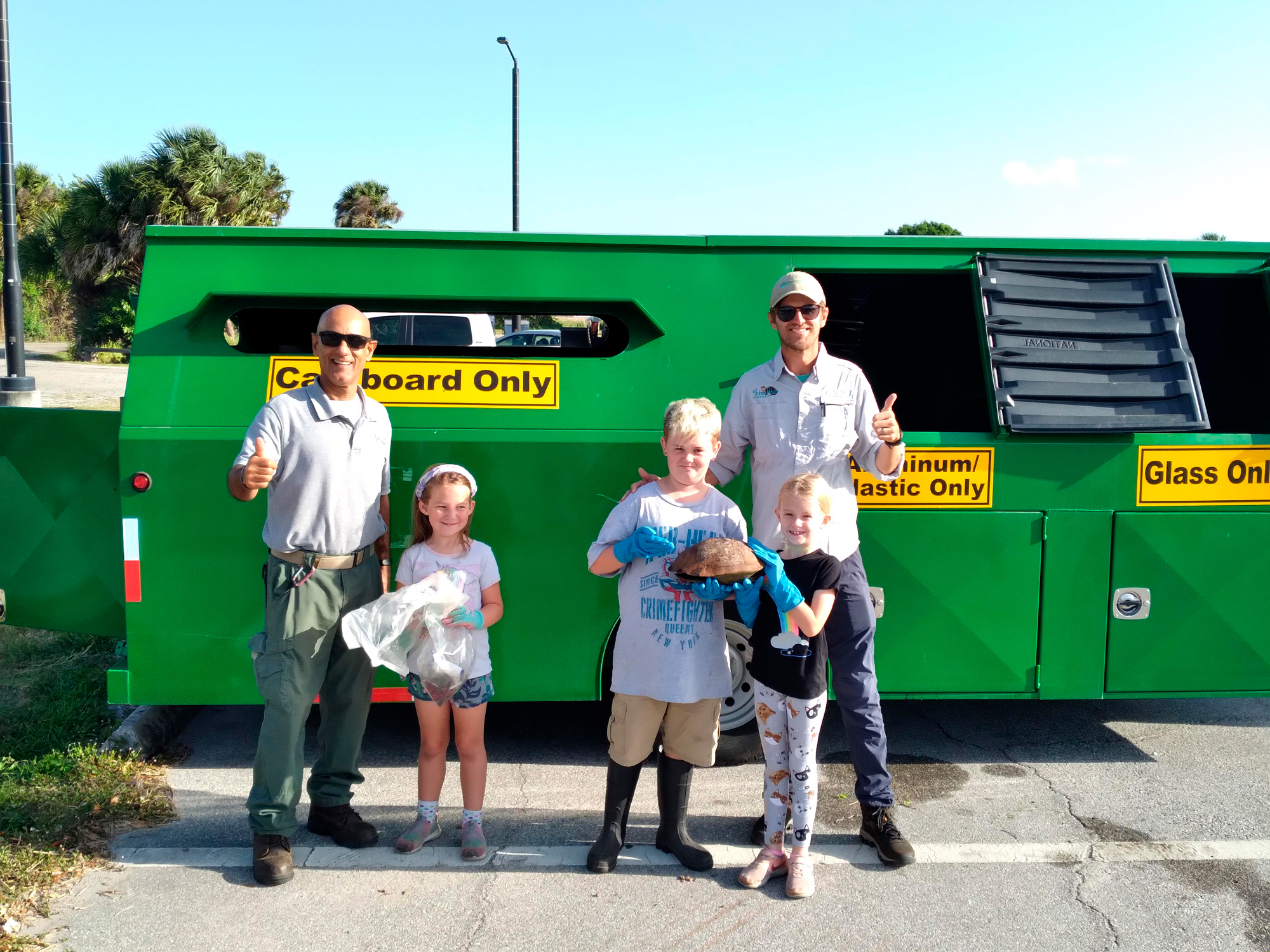 two seminole county solid waste management employees and three children standing outside in front of "BART" the recycling trailer