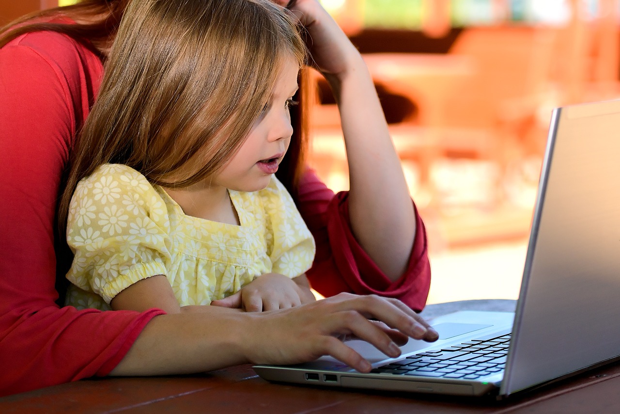 Mom and toddler daughter attending a virtual library program on the laptop